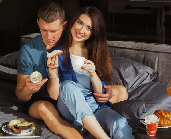 Romantic Couple Sitting on the Bed while Eating Together