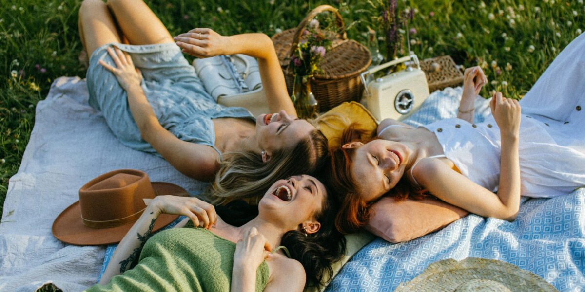 Photo by KoolShooters : https://www.pexels.com/photo/a-group-of-women-lying-on-a-picnic-blanket-while-having-fun-8531237/