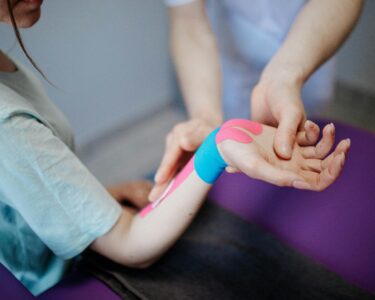 Photo by Danik Prihodko: https://www.pexels.com/photo/person-applying-kinesio-tape-on-a-girl-s-arm-and-wrist-8219158/