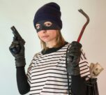 Photo by Vika Glitter: https://www.pexels.com/photo/a-woman-in-striped-shirt-carrying-a-black-bag-while-holding-a-gun-7916847/