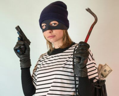 Photo by Vika Glitter: https://www.pexels.com/photo/a-woman-in-striped-shirt-carrying-a-black-bag-while-holding-a-gun-7916847/