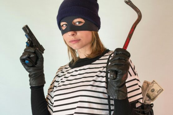 Photo by Vika Glitter: https://www.pexels.com/photo/a-woman-in-striped-shirt-carrying-a-black-bag-while-holding-a-gun-7916847/