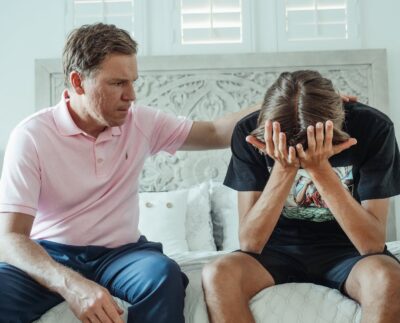 Photo by Kindel Media: https://www.pexels.com/photo/man-in-a-pink-shirt-sitting-beside-a-teenager-crying-8550682/